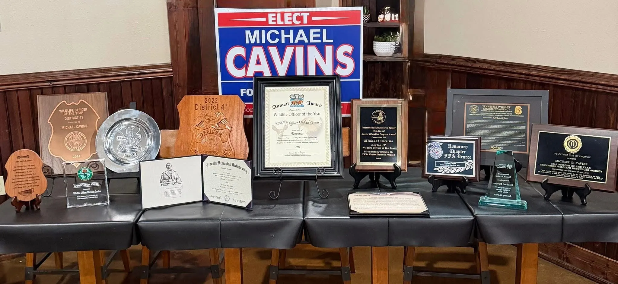 A table displaying Michael Cavins’ service awards, including Wildlife Officer of the Year honors and his Lincoln Memorial University degree
