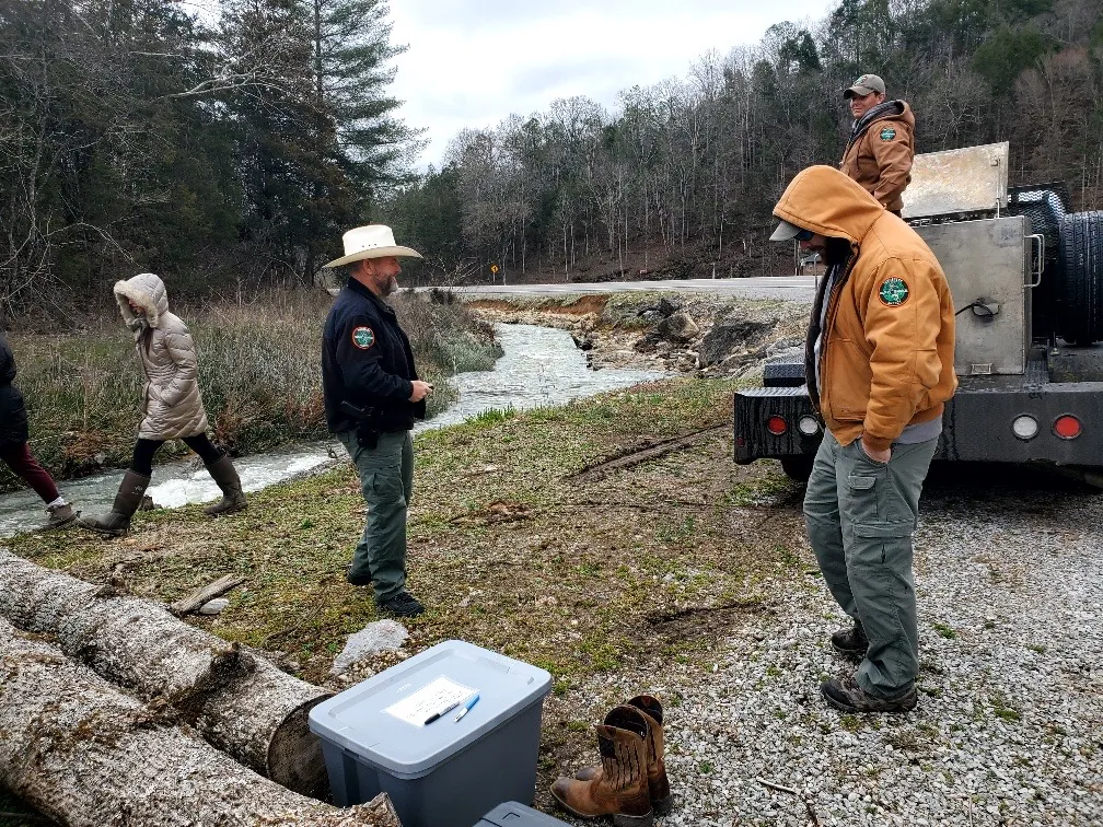 Game wardens working alongside residents at a creek beside a rural Claiborne County road