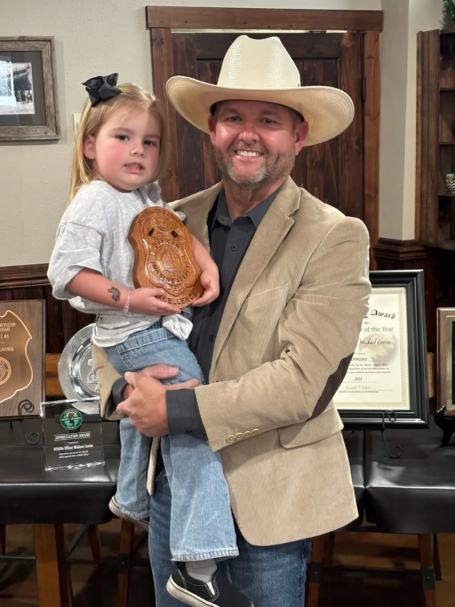 Michael Cavins holding Ivy, who holds his carved wildlife officer award, at the Nineteen19 meet and greet