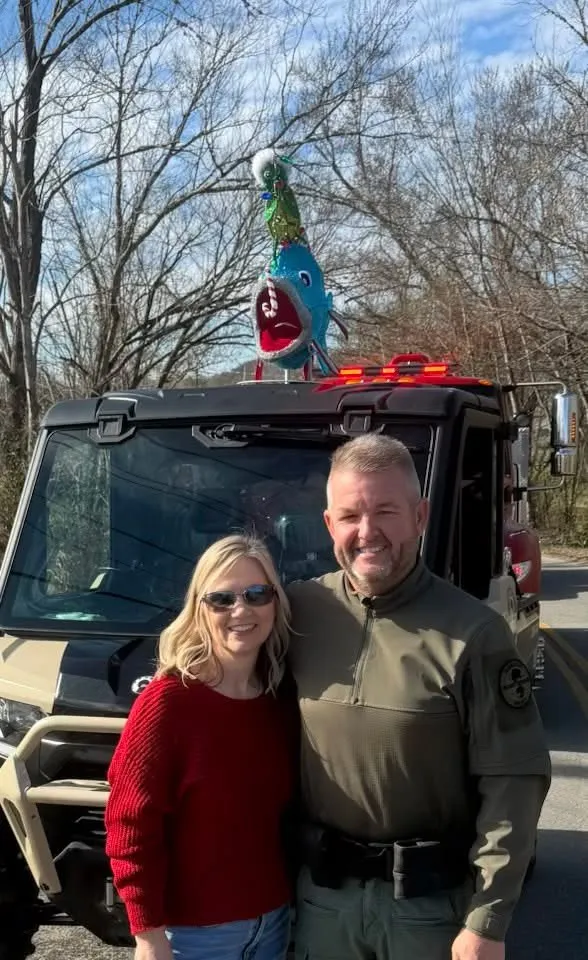 Michael and Pamela Cavins smiling in front of a parade vehicle decorated for Christmas